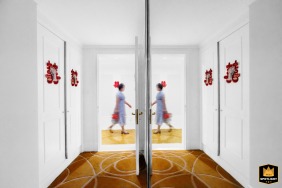 Inside a hotel room in Shanxi, the groom’s mother paces thoughtfully, her presence adding warmth and tradition to the preparations unfolding before the ceremony.